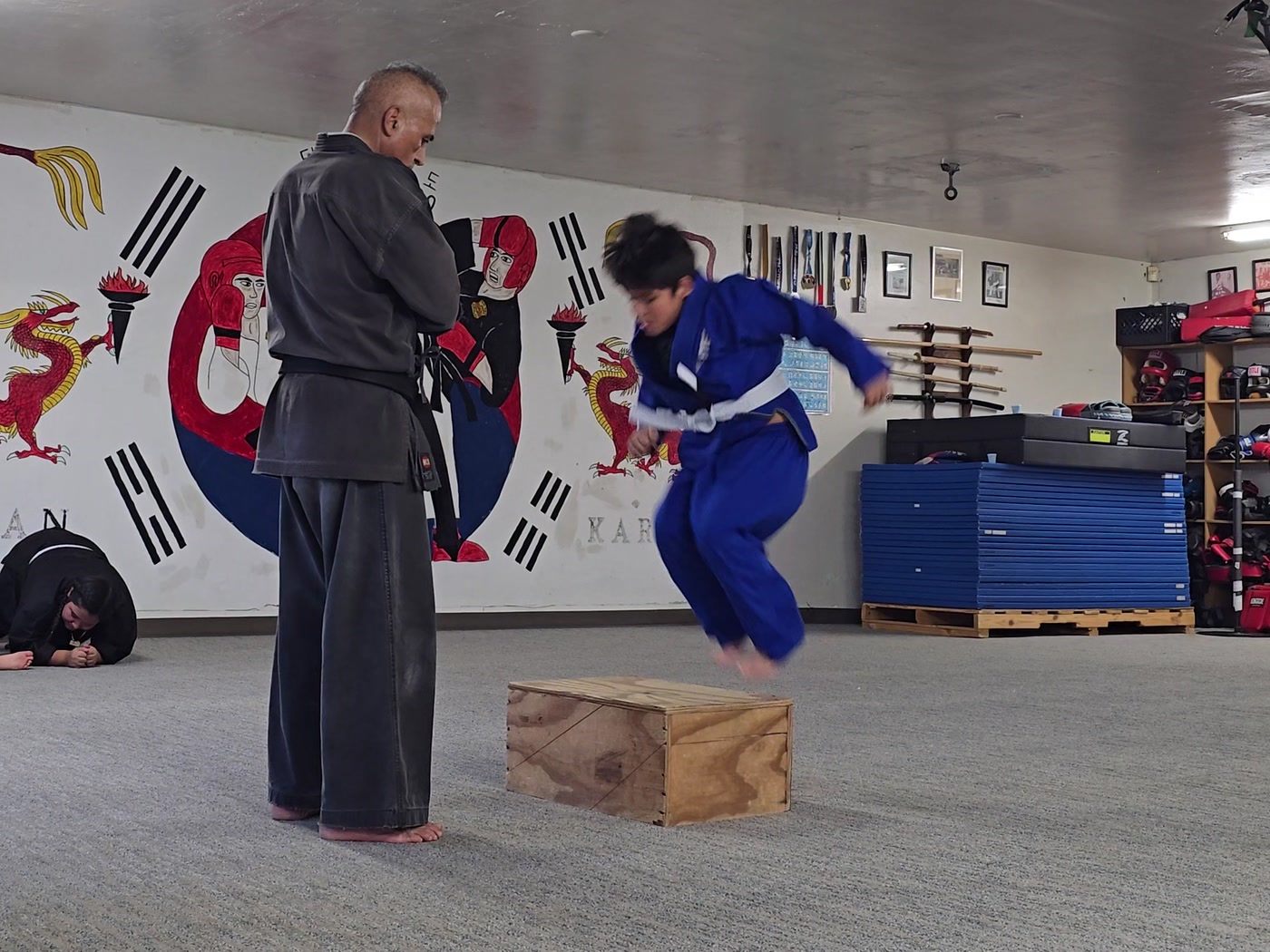 Box jumps in front of the mural, instructor Mundo watching.