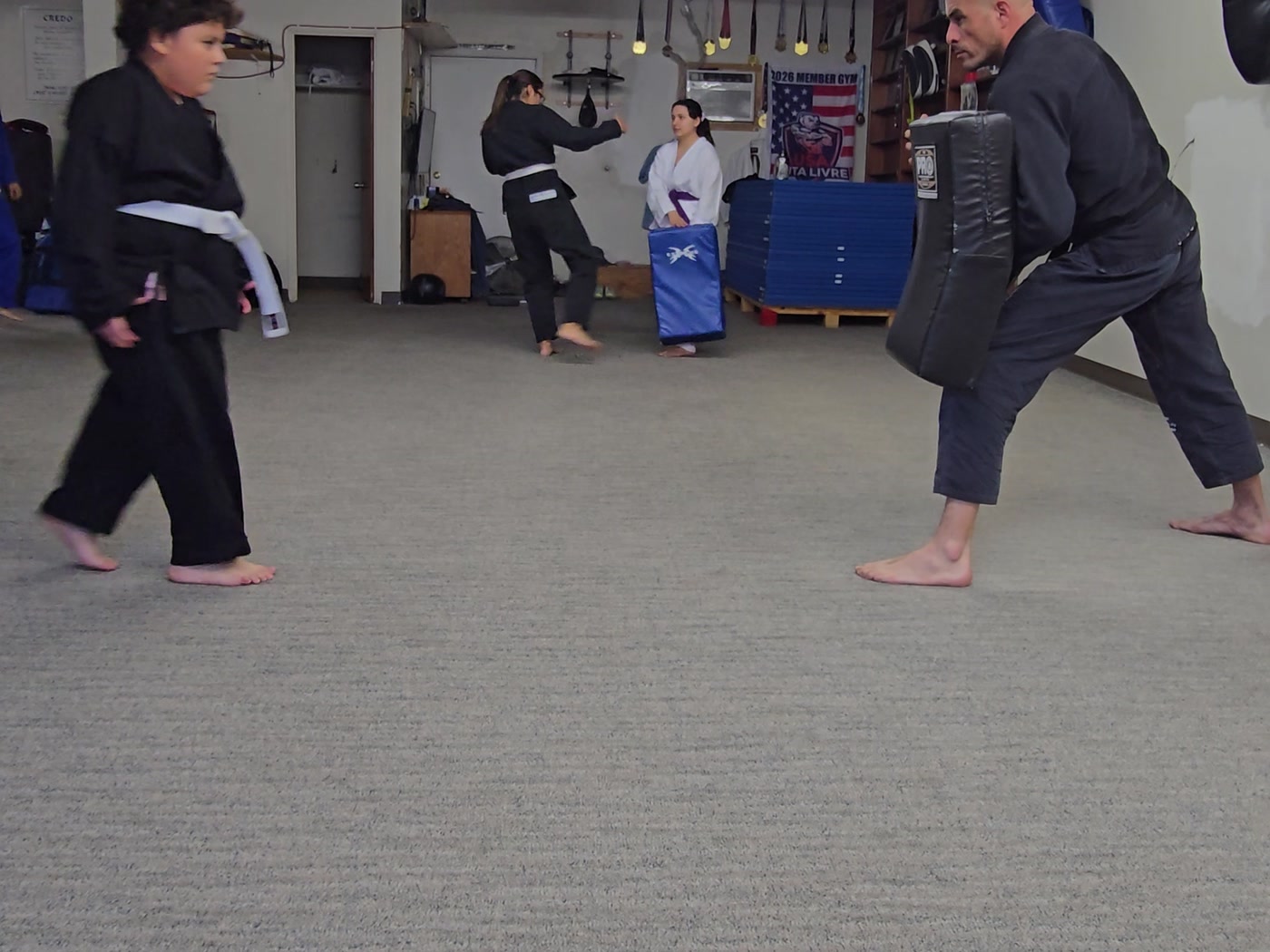 Young student lining up a kick on the shield held by the instructor.